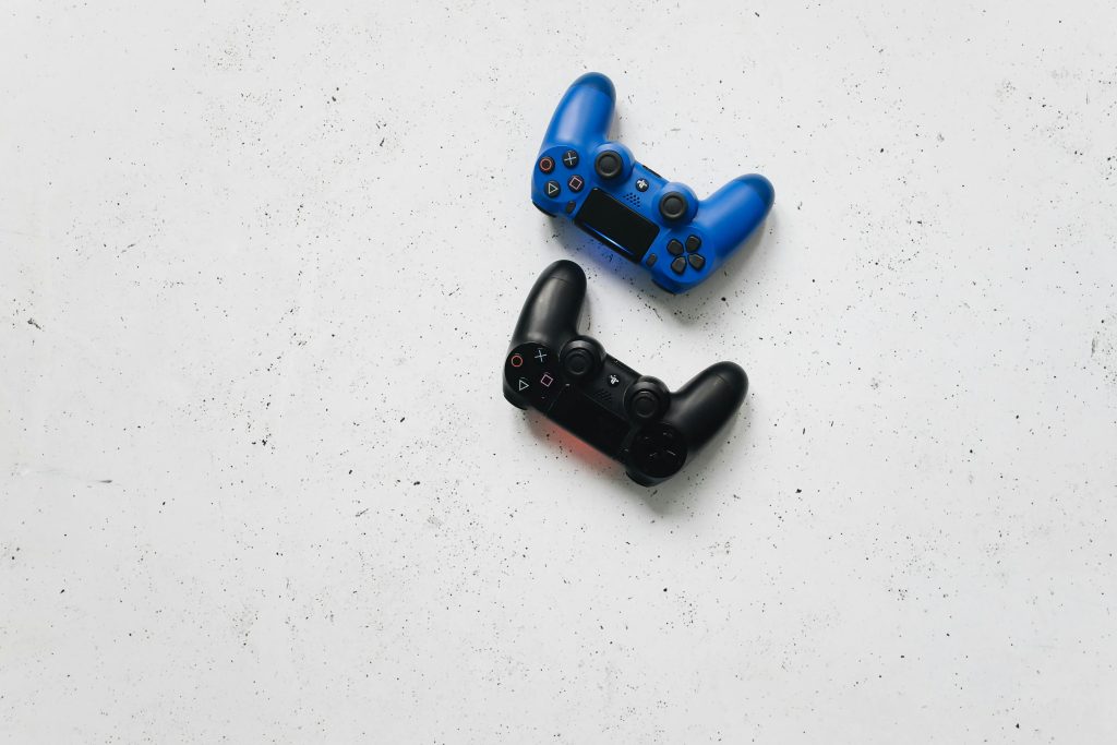 Blue and black PlayStation controllers on a white speckled surface captured from above.